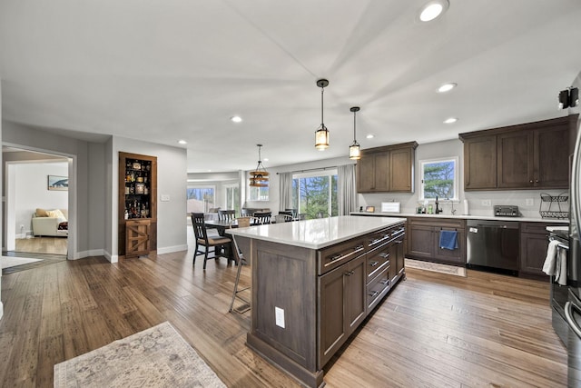 11378 Ann Dr NW, Baltimore, OH 43105 - kitchen with stainless steel dishwasher, dark brown cabinetry, light countertops, and a breakfast bar area