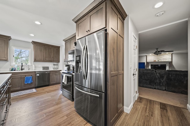 11378 Ann Dr NW, Baltimore, OH 43105 - kitchen with a large fireplace, recessed lighting, light countertops, stainless steel appliances, and light wood finished floors