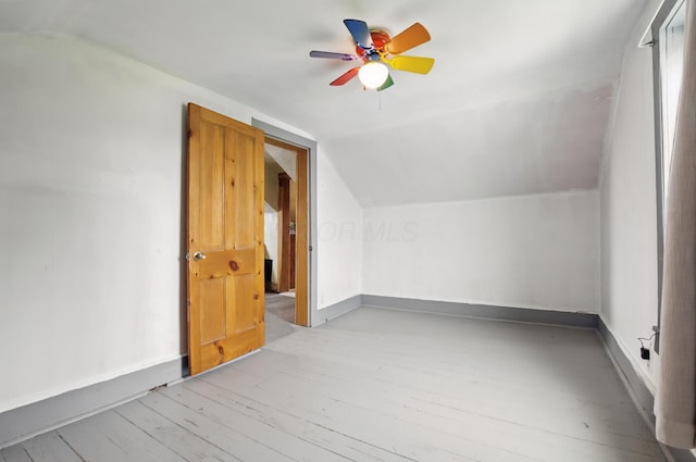 additional living space with light wood-style flooring, a ceiling fan, vaulted ceiling, and baseboards