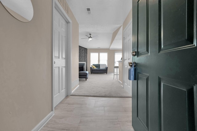 hallway featuring light colored carpet, baseboards, and visible vents