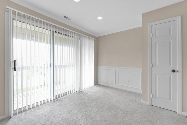 unfurnished room featuring crown molding, visible vents, carpet flooring, and wainscoting