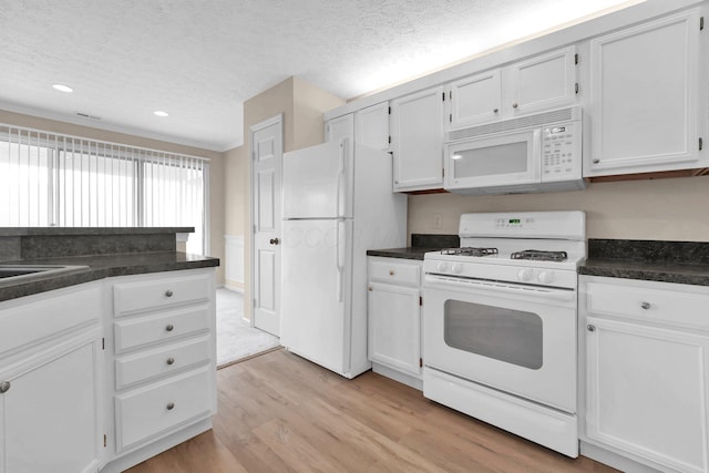 kitchen with white cabinets, light wood-type flooring, dark countertops, recessed lighting, and white appliances