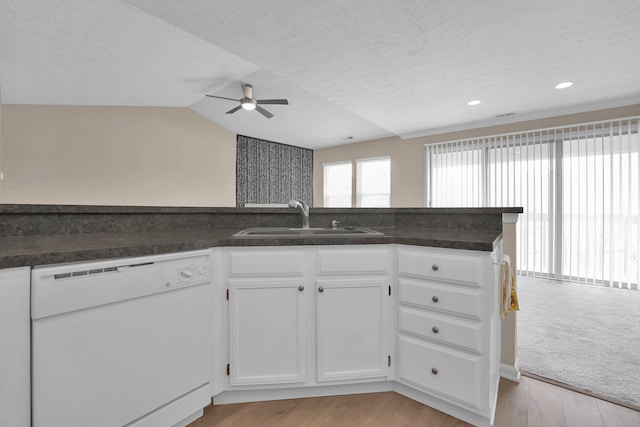 kitchen with white dishwasher, dark countertops, ceiling fan, and a sink