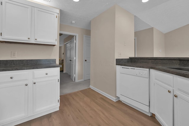 kitchen with white dishwasher, dark countertops, light wood-type flooring, and white cabinets