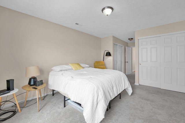 carpeted bedroom featuring visible vents, baseboards, and multiple closets