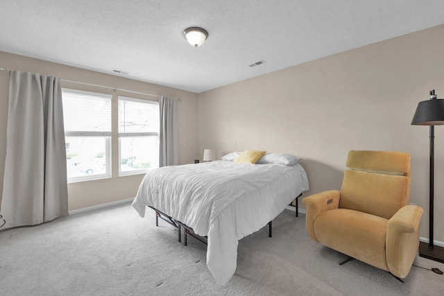 bedroom featuring a textured ceiling, carpet, visible vents, and baseboards