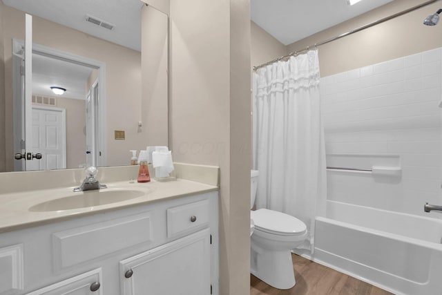 bathroom with toilet, vanity, wood finished floors, and visible vents