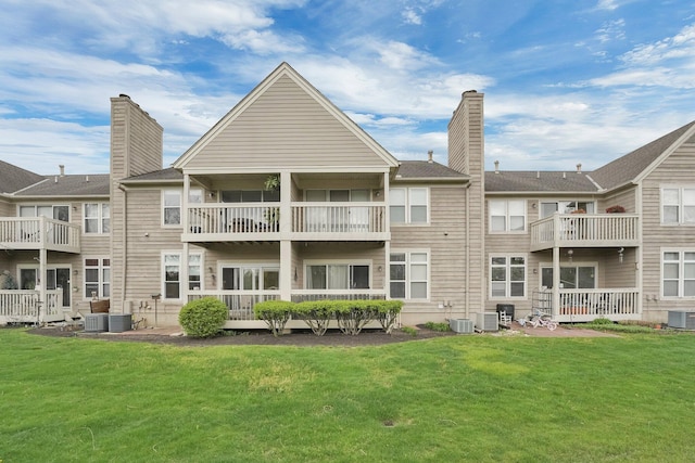 back of house with a chimney, central AC unit, a balcony, and a lawn