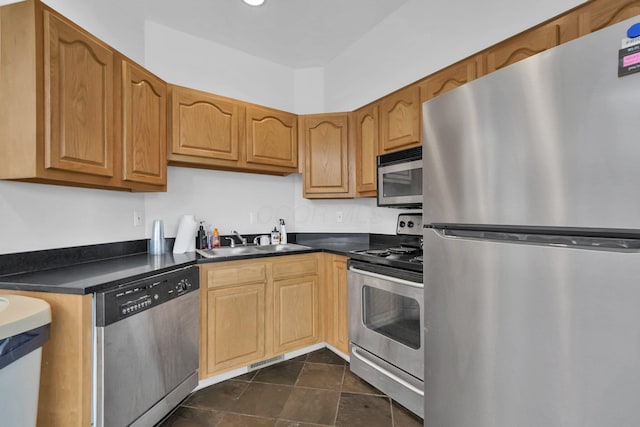 kitchen featuring stainless steel appliances, dark countertops, visible vents, a sink, and dark tile patterned flooring