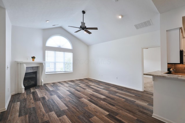 8050 Flint Run Pl, Columbus, OH 43235 - unfurnished living room featuring ceiling fan, a tiled fireplace, dark wood-style floors, vaulted ceiling, and baseboards