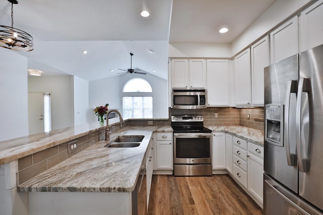 8050 Flint Run Pl, Columbus, OH 43235 - kitchen featuring appliances with stainless steel finishes, a sink, wood finished floors, light stone countertops, and a peninsula