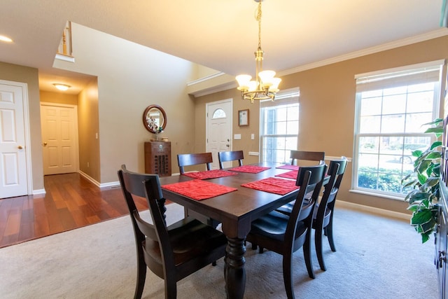 dining space featuring a chandelier, carpet floors, crown molding, and baseboards