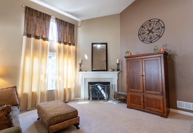 living area with high vaulted ceiling, light carpet, visible vents, and a fireplace