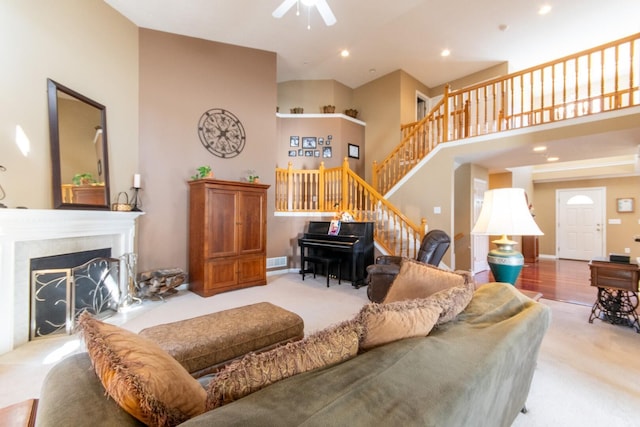 living area with visible vents, a ceiling fan, a high ceiling, stairway, and carpet floors