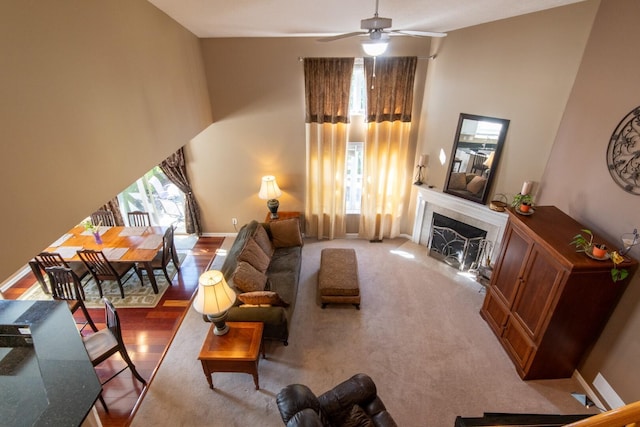 living room featuring a tile fireplace, ceiling fan, a wealth of natural light, and a towering ceiling