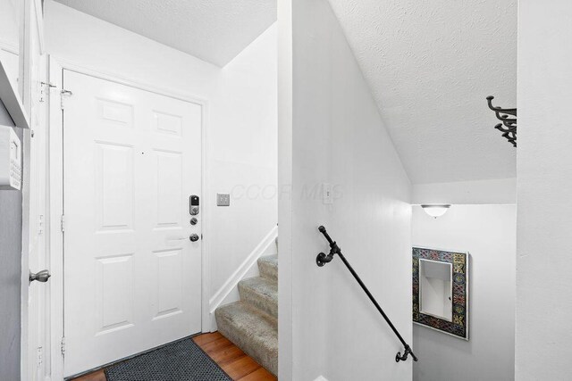 3379 Fishinger Mill Dr, Hilliard, OH 43026 - entrance foyer featuring a textured ceiling, wood finished floors, stairway, and vaulted ceiling