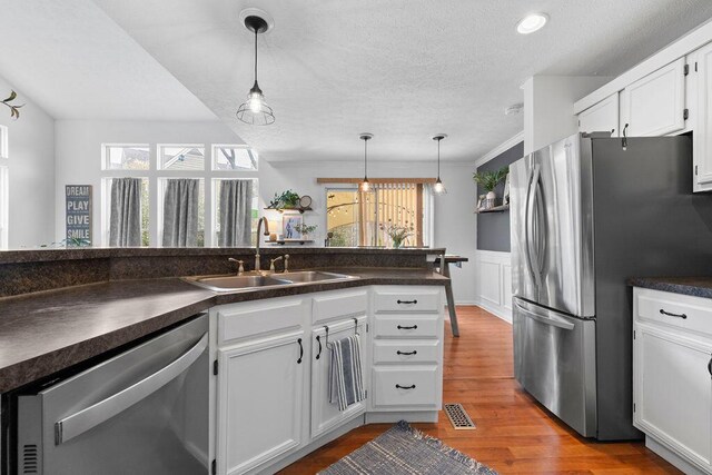 3379 Fishinger Mill Dr, Hilliard, OH 43026 - kitchen with stainless steel appliances, a sink, dark countertops, white cabinets, and pendant lighting