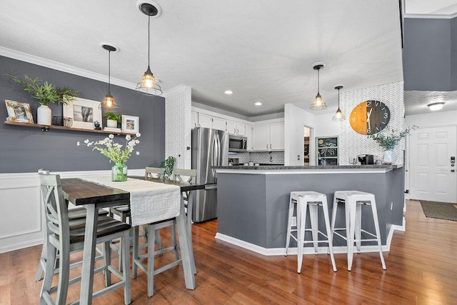 3379 Fishinger Mill Dr, Hilliard, OH 43026 - kitchen featuring stainless steel appliances, a peninsula, tasteful backsplash, white cabinets, and wood finished floors