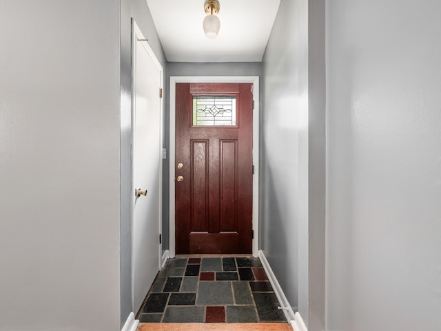 doorway featuring baseboards and dark stone finish flooring
