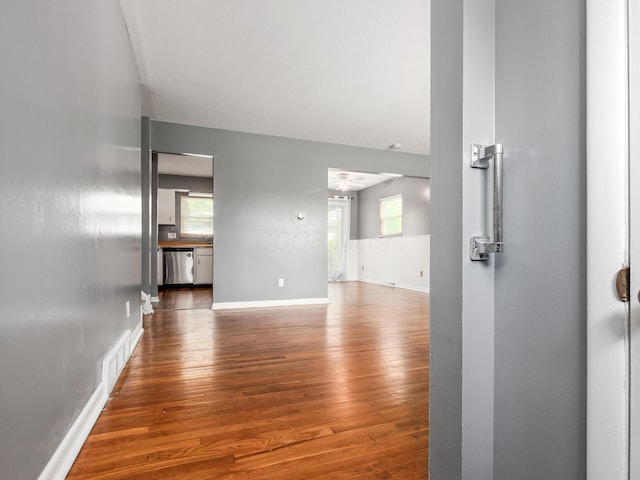 unfurnished living room featuring wood finished floors, baseboards, and healthy amount of natural light
