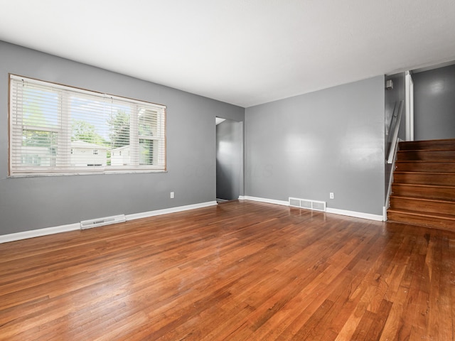 unfurnished room featuring wood finished floors, stairway, and baseboards
