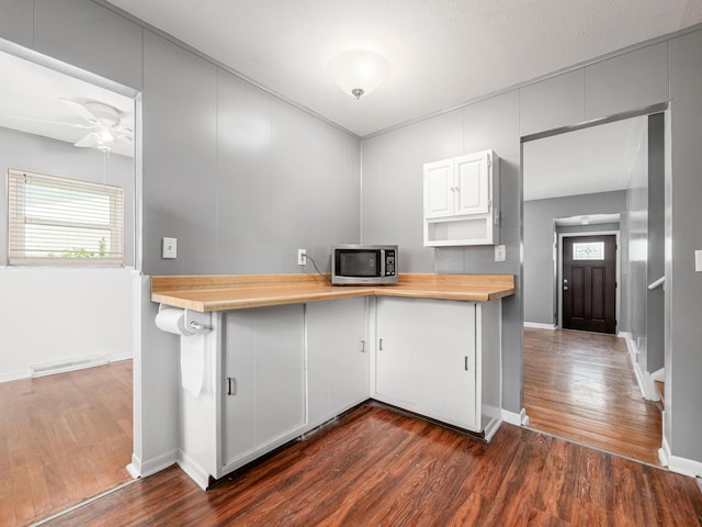 kitchen with stainless steel microwave, wood counters, dark wood-style flooring, and baseboards