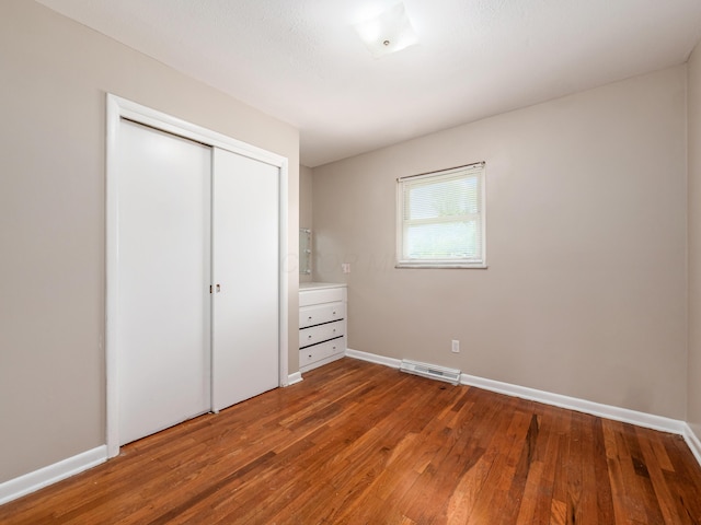 unfurnished bedroom featuring hardwood / wood-style flooring, baseboards, and a closet
