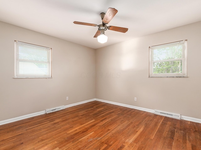 unfurnished room featuring plenty of natural light, baseboards, wood finished floors, and a ceiling fan