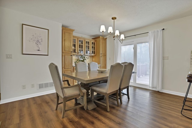 dining area with dark wood-style floors, baseboards, an inviting chandelier, and visible vents