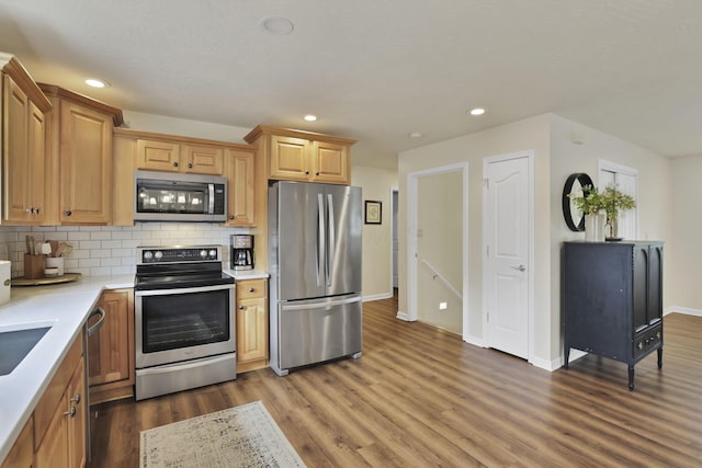 kitchen featuring recessed lighting, light countertops, backsplash, appliances with stainless steel finishes, and wood finished floors