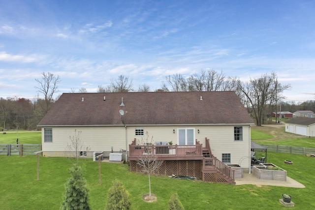 rear view of property featuring fence, a deck, and a lawn