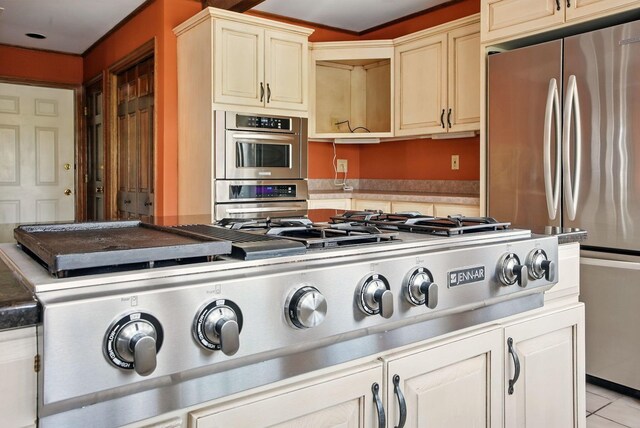 kitchen with cream cabinetry, light tile patterned flooring, and stainless steel appliances