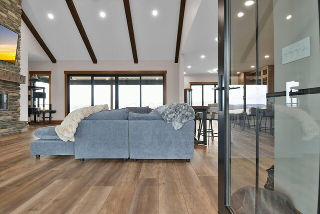 living area featuring a fireplace, recessed lighting, beam ceiling, high vaulted ceiling, and wood finished floors
