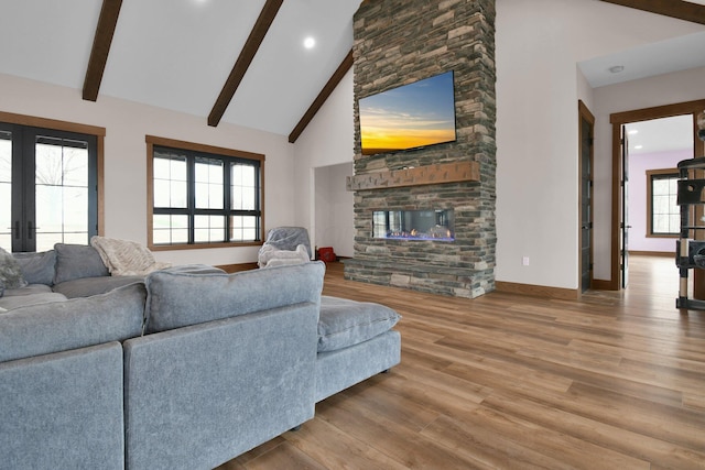 living room featuring high vaulted ceiling, a stone fireplace, wood finished floors, baseboards, and beam ceiling