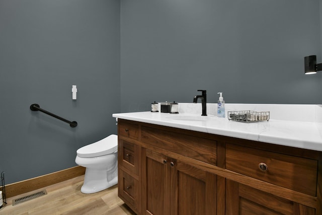 bathroom featuring visible vents, baseboards, toilet, vanity, and wood finished floors
