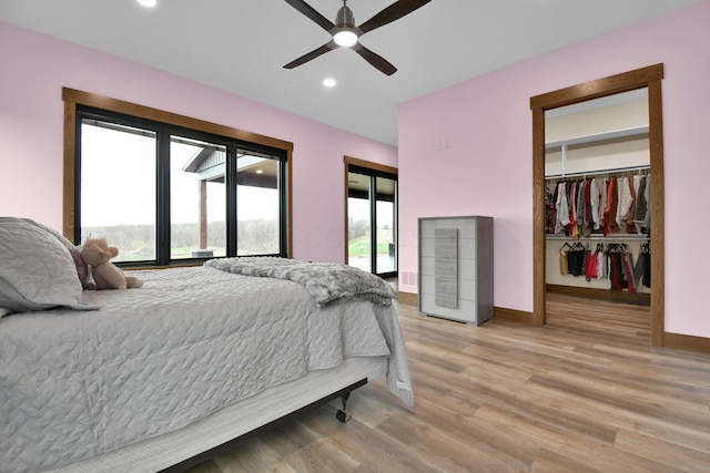 bedroom featuring baseboards, a spacious closet, recessed lighting, access to exterior, and light wood finished floors