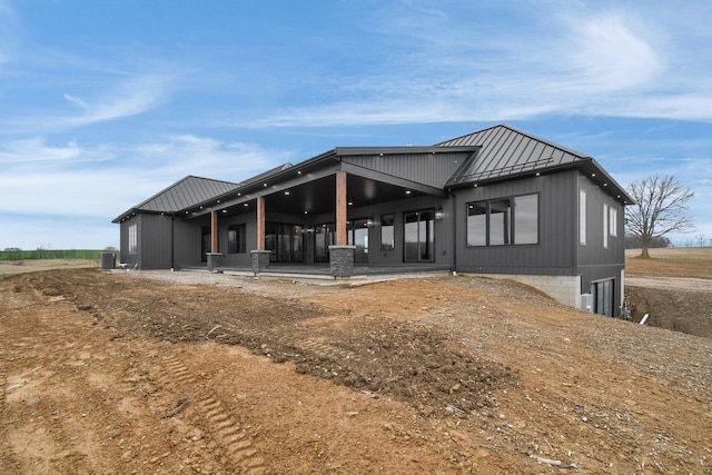 back of property featuring central air condition unit, metal roof, and a standing seam roof