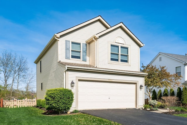 traditional-style house with a garage, fence, and aphalt driveway