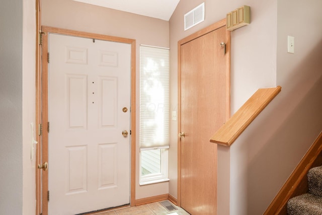 foyer entrance featuring baseboards, visible vents, and stairway