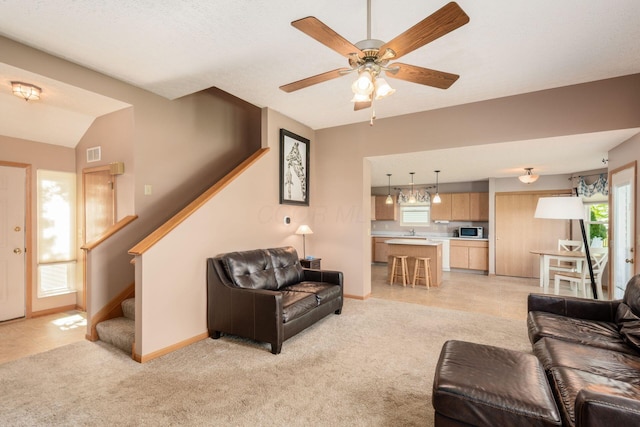 living room featuring light colored carpet, a ceiling fan, baseboards, visible vents, and stairway