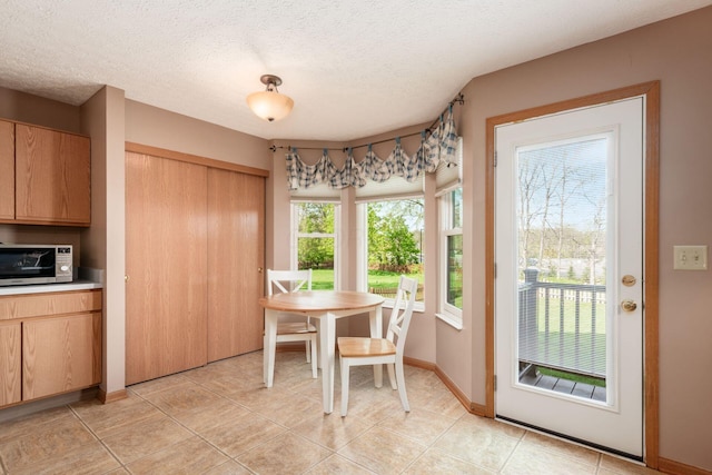 dining area featuring light tile patterned floors, baseboards, and a textured ceiling