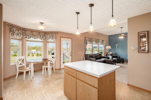 kitchen with light countertops, light tile patterned floors, a ceiling fan, and a wealth of natural light