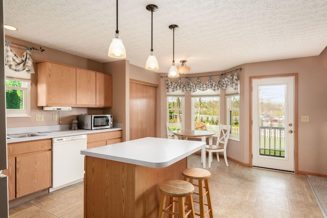 kitchen with white dishwasher, light countertops, light brown cabinetry, and stainless steel microwave