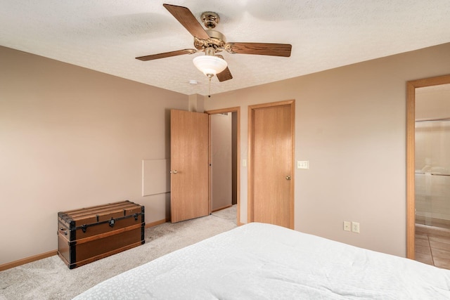 bedroom featuring ceiling fan, a textured ceiling, light colored carpet, baseboards, and ensuite bathroom