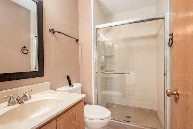 full bathroom with toilet, a textured ceiling, a shower stall, and vanity