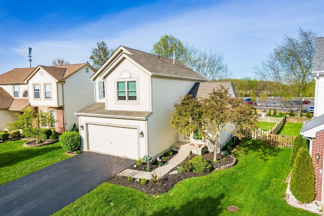 traditional home with fence, an attached garage, driveway, and a front yard