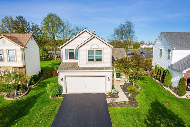 traditional home featuring fence, driveway, a front lawn, and a garage