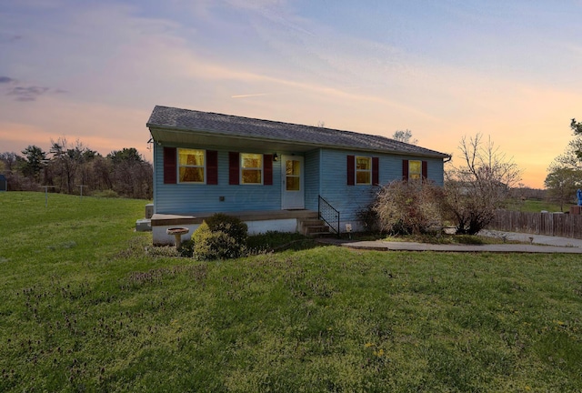 view of front of home featuring a yard, roof with shingles, and fence