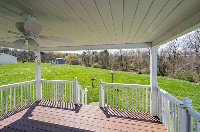 wooden deck featuring a yard, a shed, a ceiling fan, and an outdoor structure