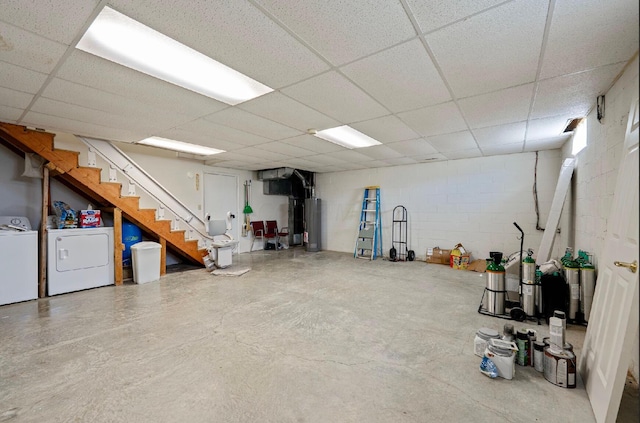 finished basement with a paneled ceiling, concrete block wall, and washing machine and dryer
